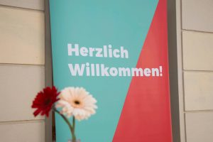 Schild und Blumen Herzlich Willkommen